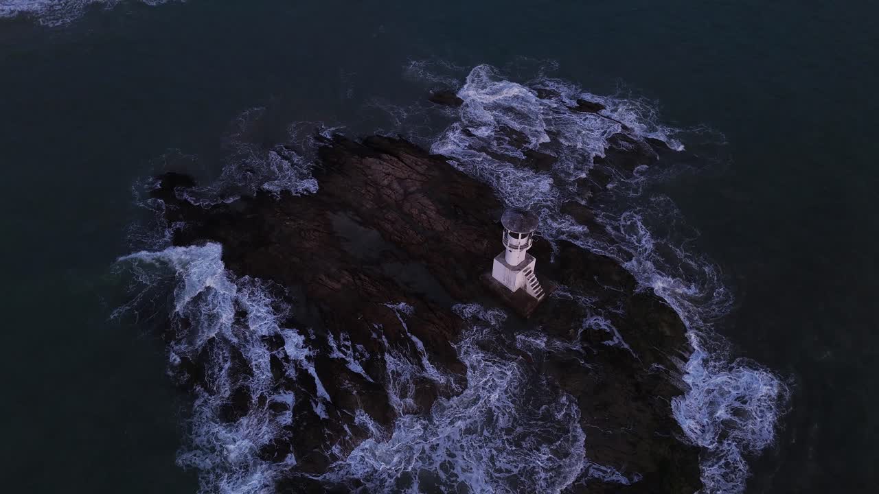 Lighthouse on Rocky Island Surrounded by Waves