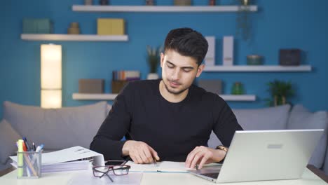 joven que trabaja en casa centrado en la computadora portátil.