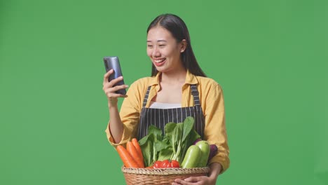 woman with vegetables looking at phone