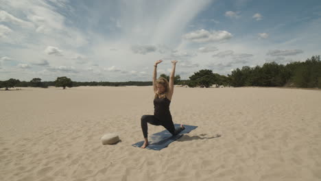 Mujer-Estirándose-En-Una-Estera-De-Yoga-En-Dunas-De-Arena