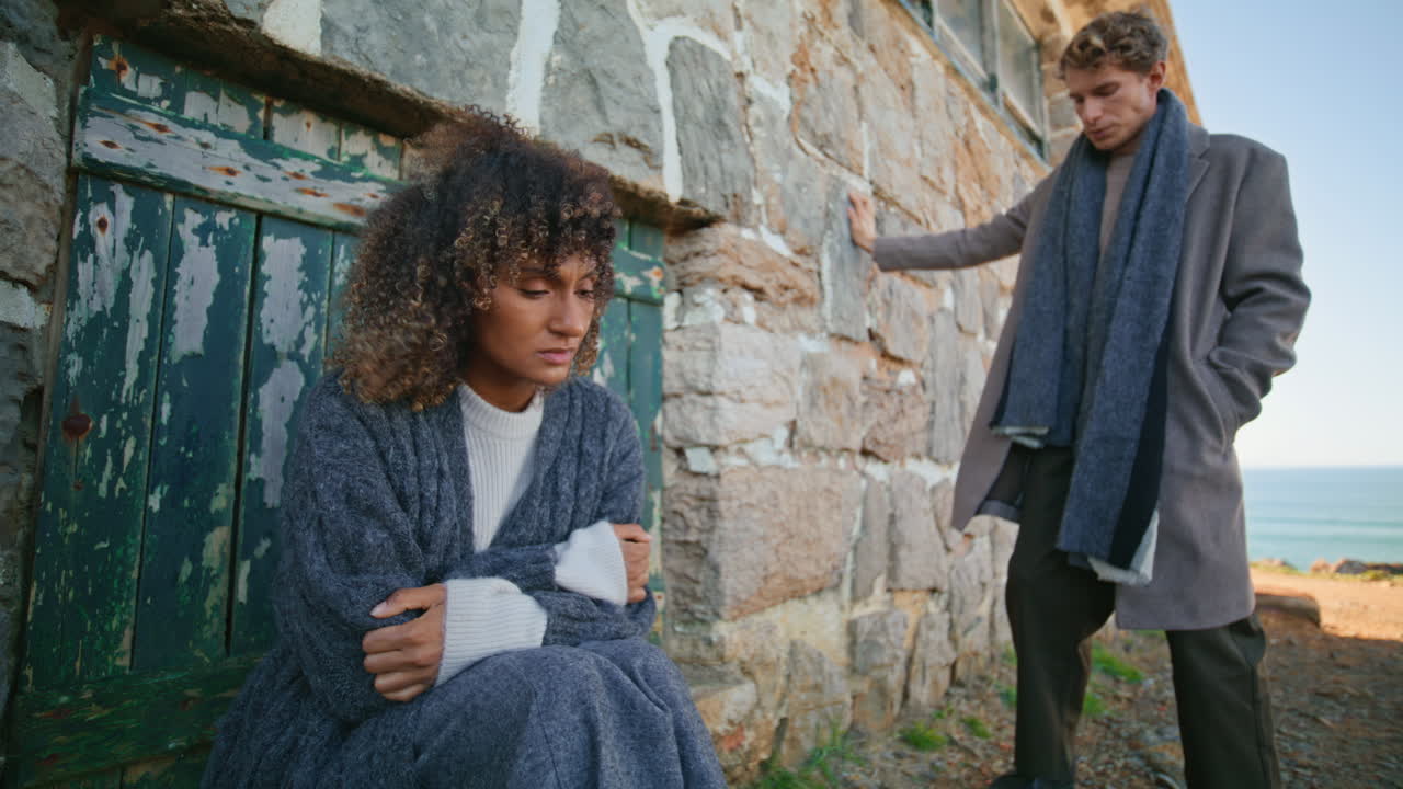 Sad couple standing castle rocks ocean landscape zoom on. Upset woman near door