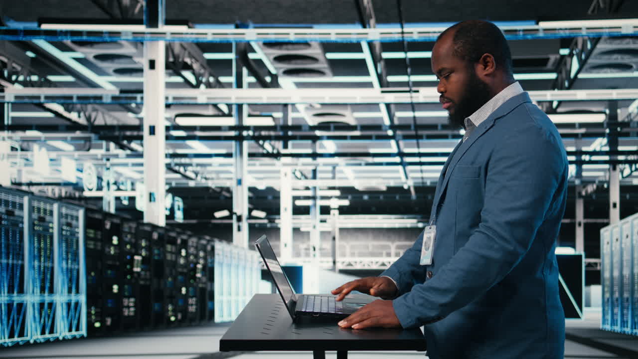 IT Professional Typing on Laptop in Modern Data Center
