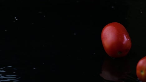 slow motion cherry tomatoes splash down on a black background