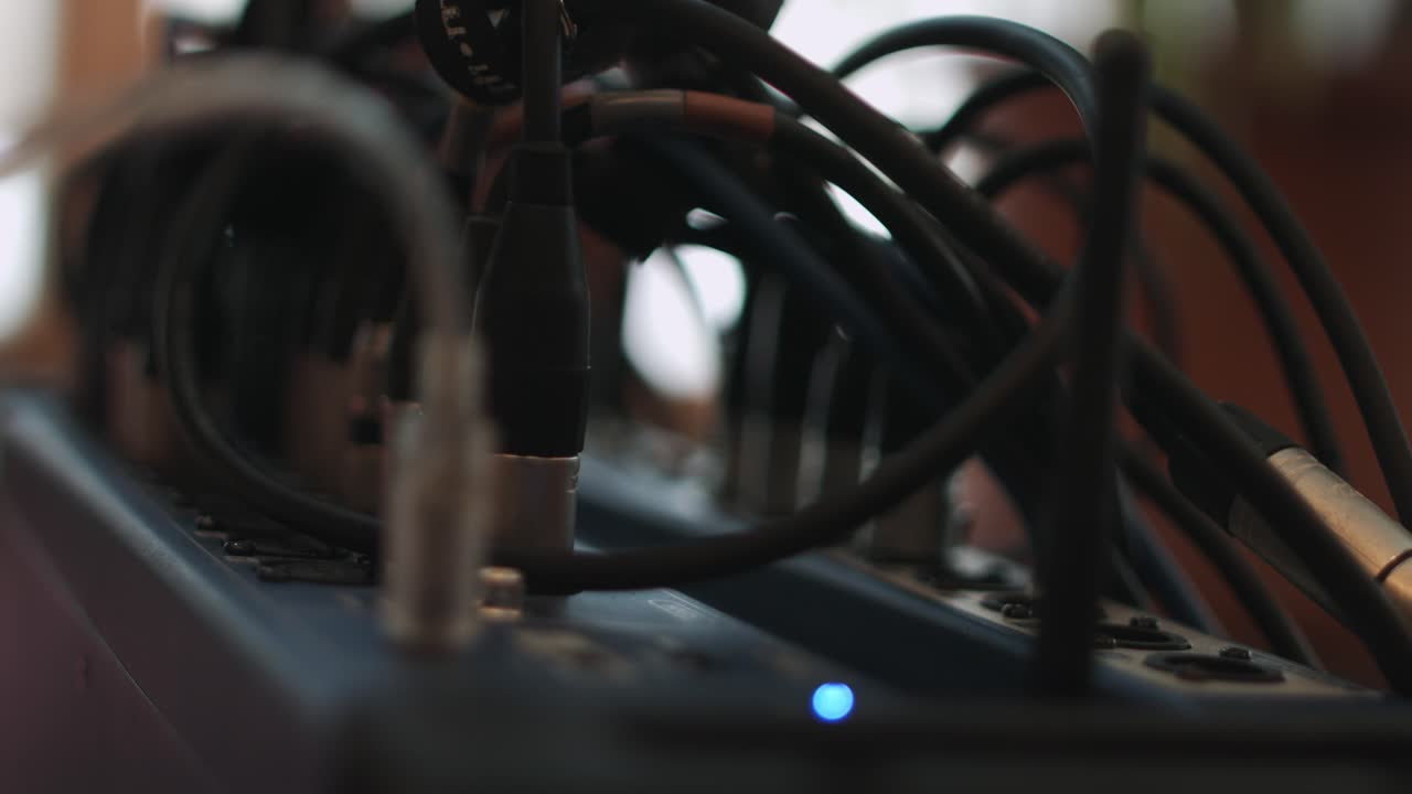 녹음 스튜디오에 있는 장치의 led 조명과 함께 여러 개의 xlr 및 usb 케이블이 연결된 오디오 휴대용 무대 믹서를 닫습니다.
