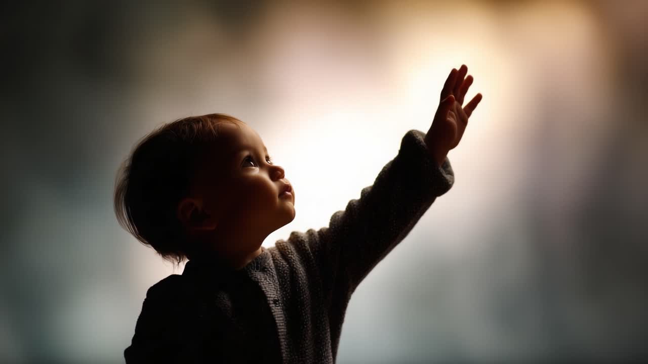 A young child reaching out with an expressive hand, silhouetted against a soft, blurred background, capturing a moment of curiosity and wonder in a beautifully lit scene