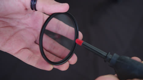 beautiful close up slow motion shot of a young man's hands cleaning a camera lens filter with an air pump to clean the dust