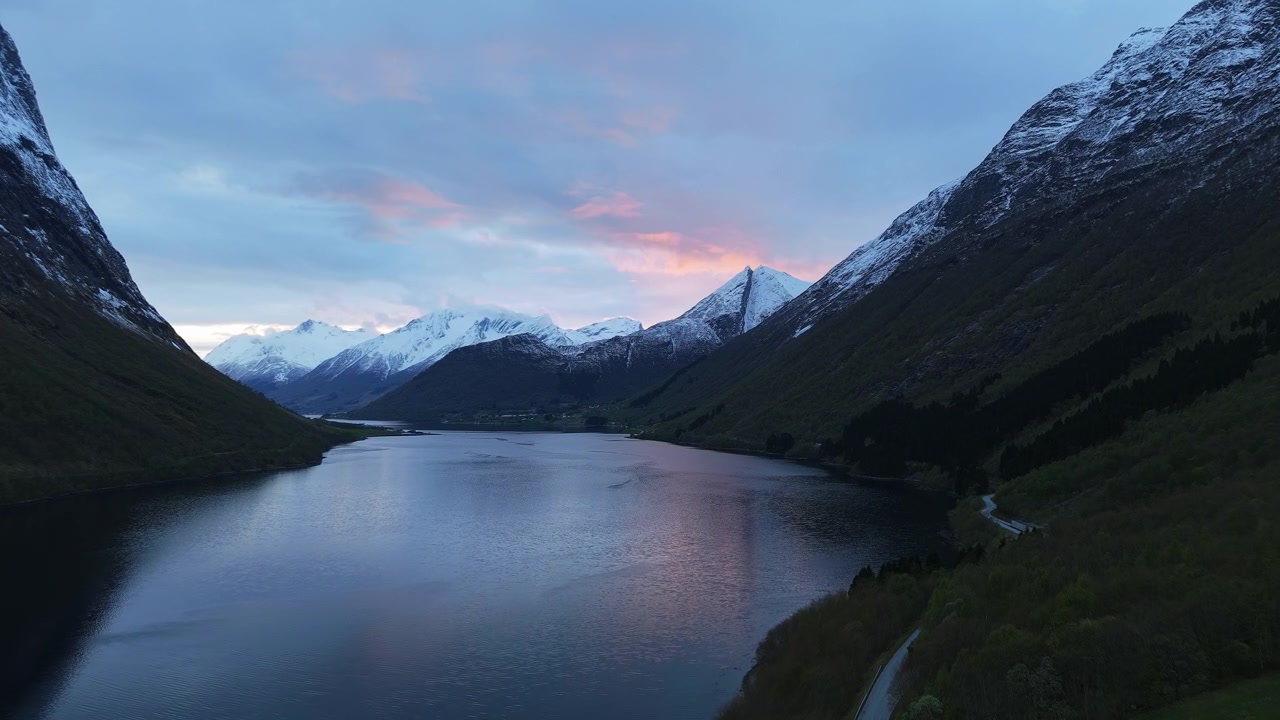 La luce soffusa dell'alba illumina un fiordo circondato da montagne innevate in Norvegia. Ideale per contenuti di viaggio e natura