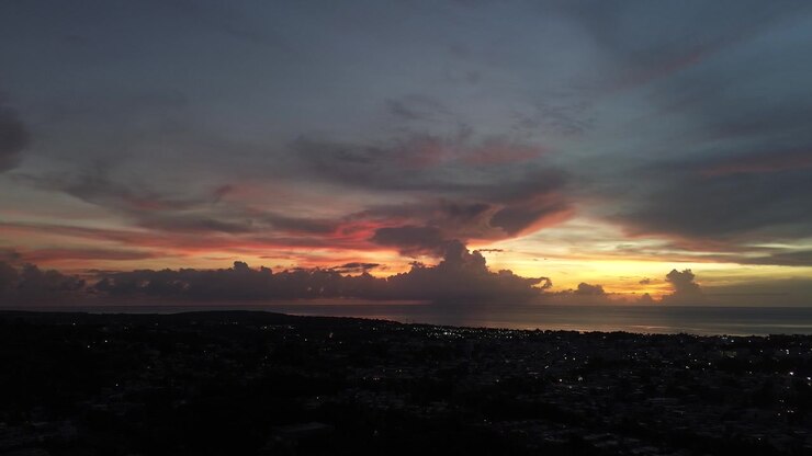 Cinematic drone pan left across a dramatic twilight sky with light storm clouds over
tropical landscape.