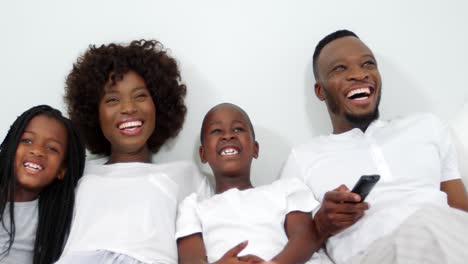 Familia-Feliz-Acostada-En-La-Cama-Y-Viendo-La-Televisión