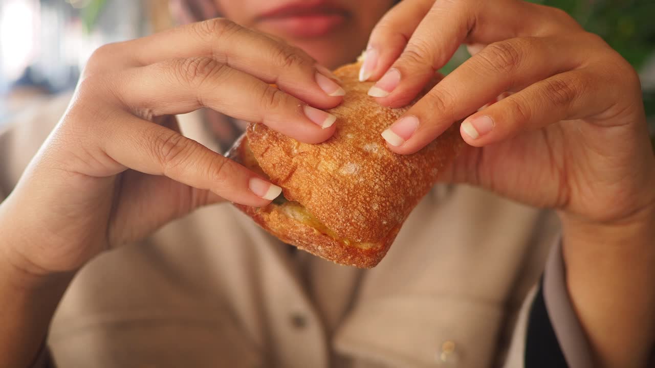 Close-up of Hands Holding and Eating a Delicious Sandwich