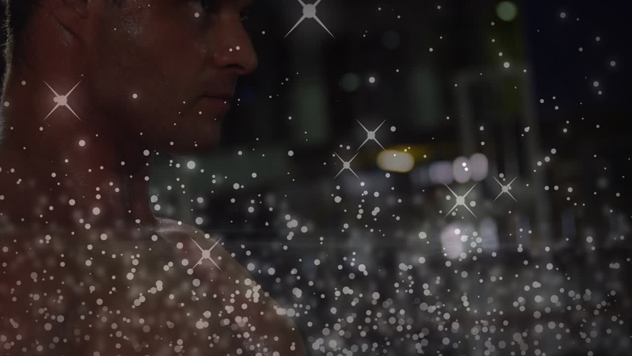 Shirtless man gazing right, camera panning revealing chest, film droplet overlay obscuring lights