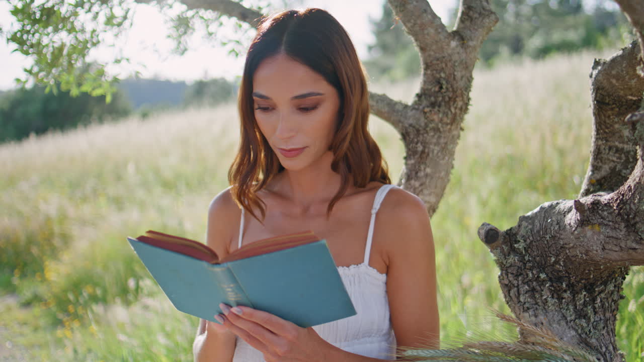 Girl reader enjoy book sitting sunny summer meadow closeup. Happy woman reading
