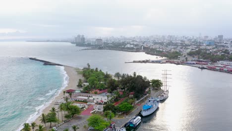 volando sobre el mar caribe en calma en la playa de punta torrecillas con santo dominigo en el fondo, tiro de drones en órbita circular aérea