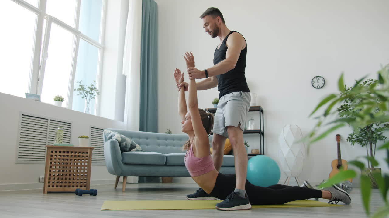 Woman performing back extension exercise with a personal trainer at home