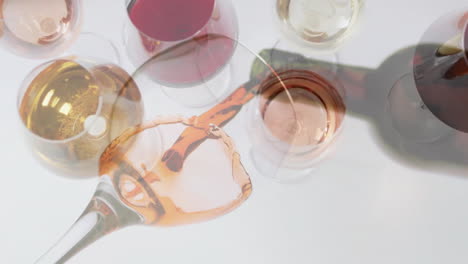 composite of rose wine being poured into glass over wine glasses on white background