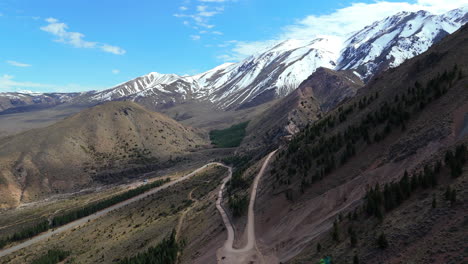 volando sobre hermosas montañas cubiertas de nieve, camino de tierra, hermoso cielo despejado, argentina, esquel, cerro la hoya.