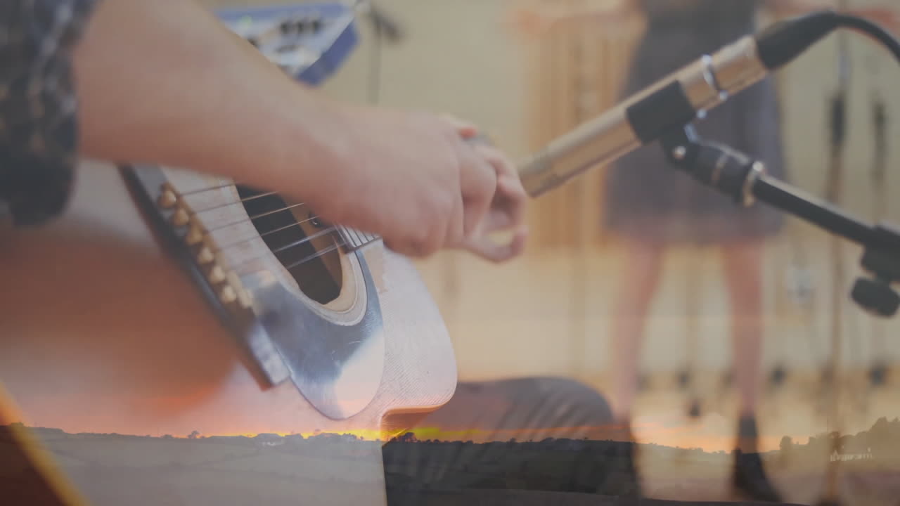 Guitarist strumming acoustic guitar in recording studio with animated audio waves near mic stands