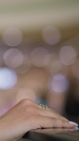 close-up of individual hand resting on iron railing, adorned with chain bracelet, red and blue strings on wrist, against soft bokeh lights in background