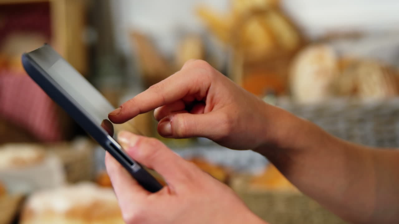 sección media de una mujer usando una tableta digital en la sección de panadería