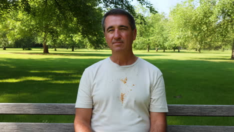 man disappointed by stain on his shirt in a park