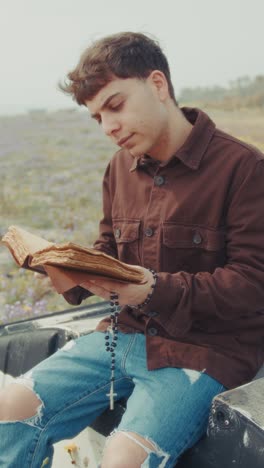 man opening the bible book and starting a prayer on the shore