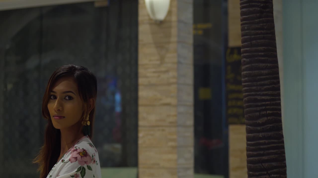 mujer joven sexy se sienta en el centro comercial antes de girar y su cabello fluye en el viento