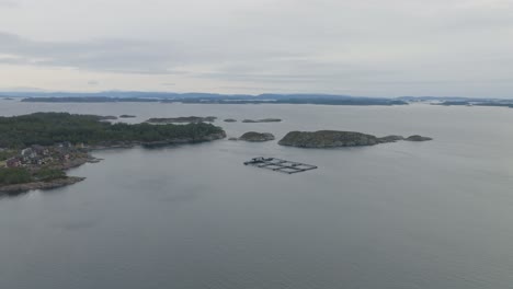 piscifactoría noruega en aguas costeras al sur de steinsland en la isla de sotra - vista aérea lejana de las instalaciones y las aguas costeras circundantes