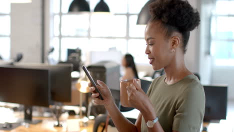 African-American-businesswoman-checks-her-phone-in-a-modern-office