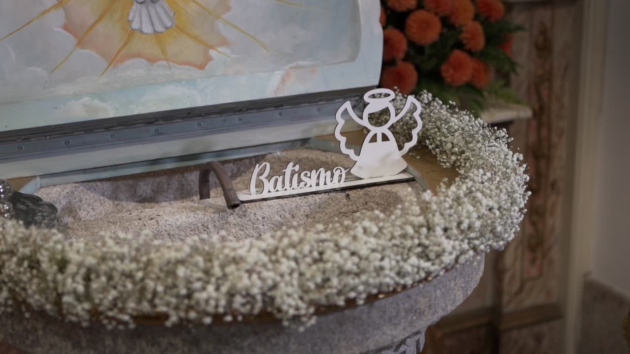 Primo piano di un simbolo battesimale e fiori sull'acquasantiera della chiesa.
