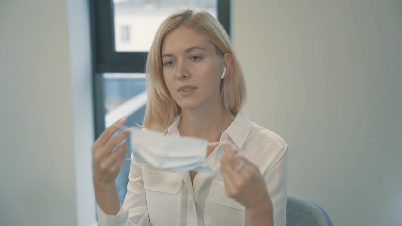 деловая женщина надевает маску на лицо для работы в закрытом помещении в офисе