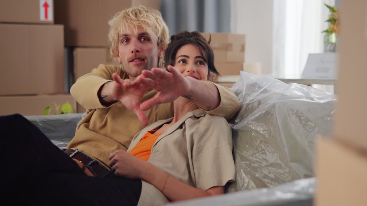 Pareja feliz discutiendo planes futuros en su nuevo apartamento.