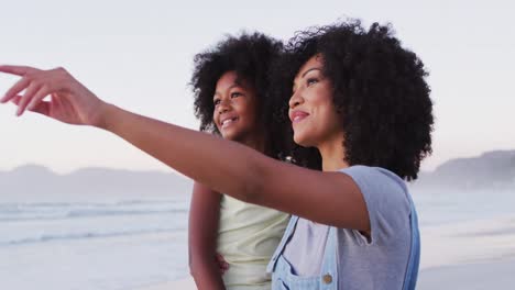 african american mother and daughter smiling looking at each other at the beach