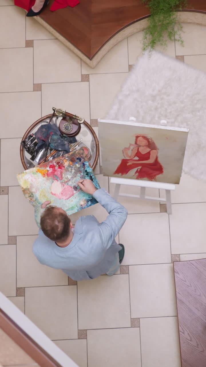 Art creator combines paints on palette in workshop. Artist combines acryl pigments for improving woman portrait in studio. Painter prepares to make picture