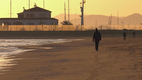 people walking on sandy beach in winter, early morning, mediterranean coast of spain