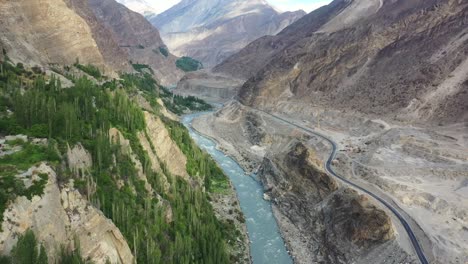 an aerial view of karakoram highway winding its way through the breathtaking landscape, accompanied by the hunza river flowing alongside