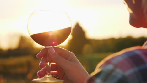 woman holds red wine at sunset