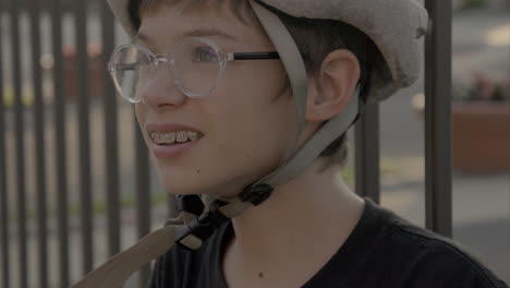 cute kid in a bike helmet and glasses looks up and off camera at golden hour