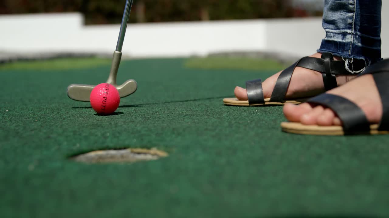 chica jugando al mini golf en el jardín 4k