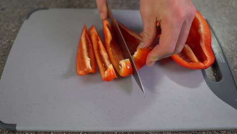 kitchen board with red paprika being chopped into small pieces