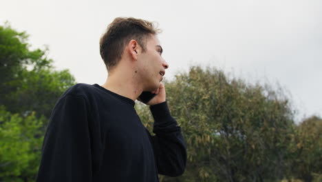 niño habla con entusiasmo en el teléfono inteligente en el parque afuera