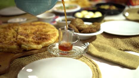 a man pours tea on a cup around egyptian breakfast, close up shot, high angle shot, insert shot