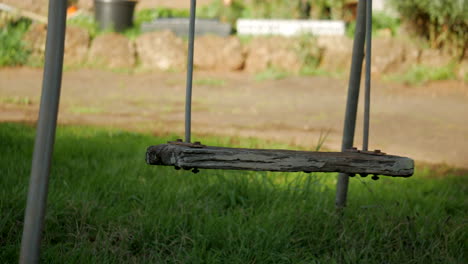 empty metal swing with rotted wooden seat