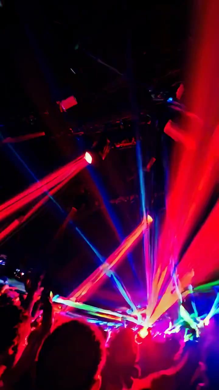Folla energica che balla con luci laser colorate in discoteca