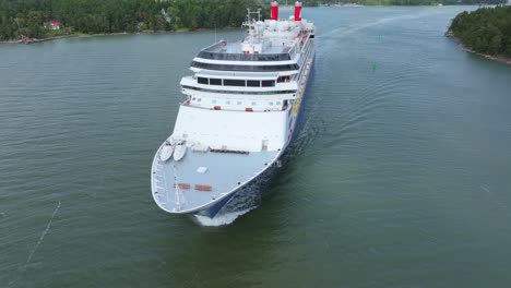 fred.olsen cruise lines passenger ship borealis making way ahead in finnish archipelago on departure. low altitude aerial view crossing bow.