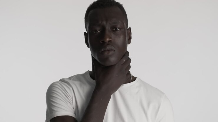 Hombre afroamericano agobiado sobre fondo gris.