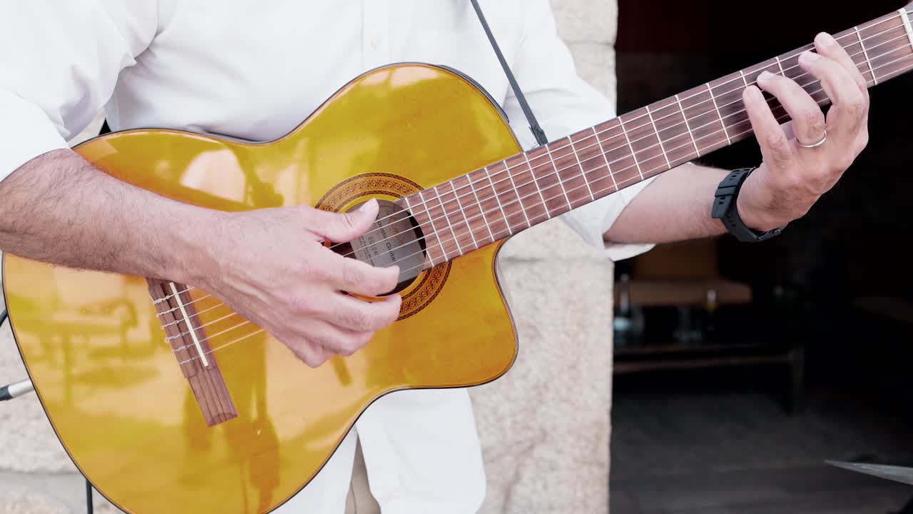 hands playing classical guitar outside in warm natural light