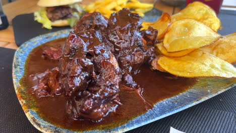 traditional spanish oxtail stew with homemade potato chips, tender slow cooked meat in red wine sauce in malaga spain, tasty food, 4k shot