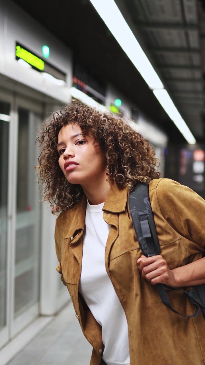 Giovane donna impaziente in attesa del treno della metropolitana sulla banchina della stazione