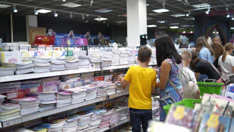 small children during school time. boy chooses school supplies for school