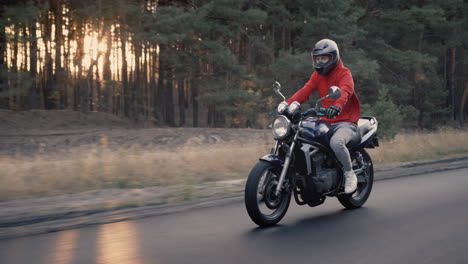 young motorcyclist quickly rides along the road along the forest 2